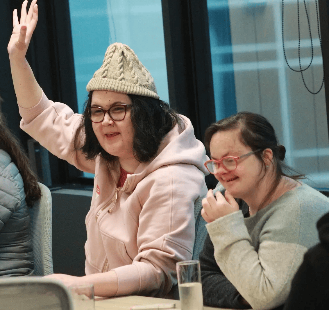 A volunteer raising her hand and smiling beside a participant during an Access Lab coaching session.